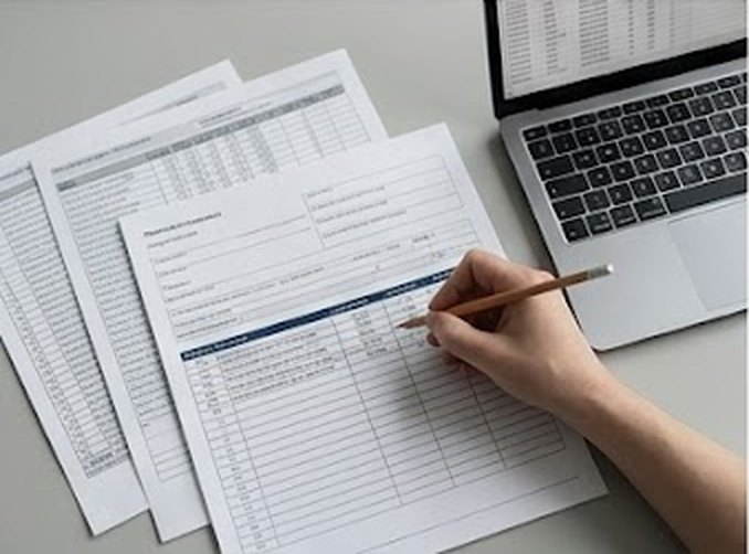 Documentación clínica en papel revisada junto a un portátil