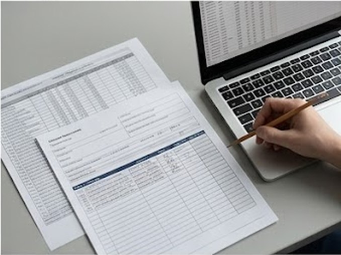 Documentación clínica impresa junto a un portátil, revisada a mano
